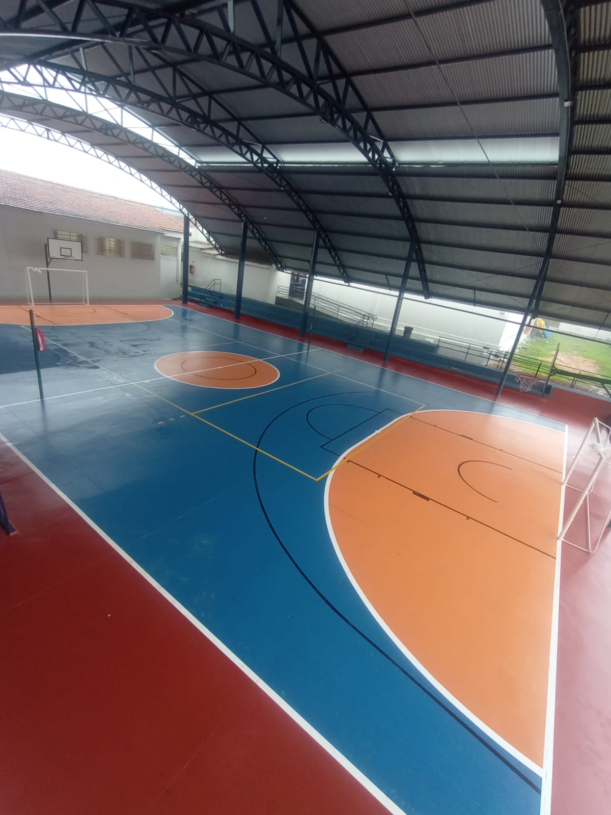 Quadra poliesportiva com demarcações brancas e piso azul
